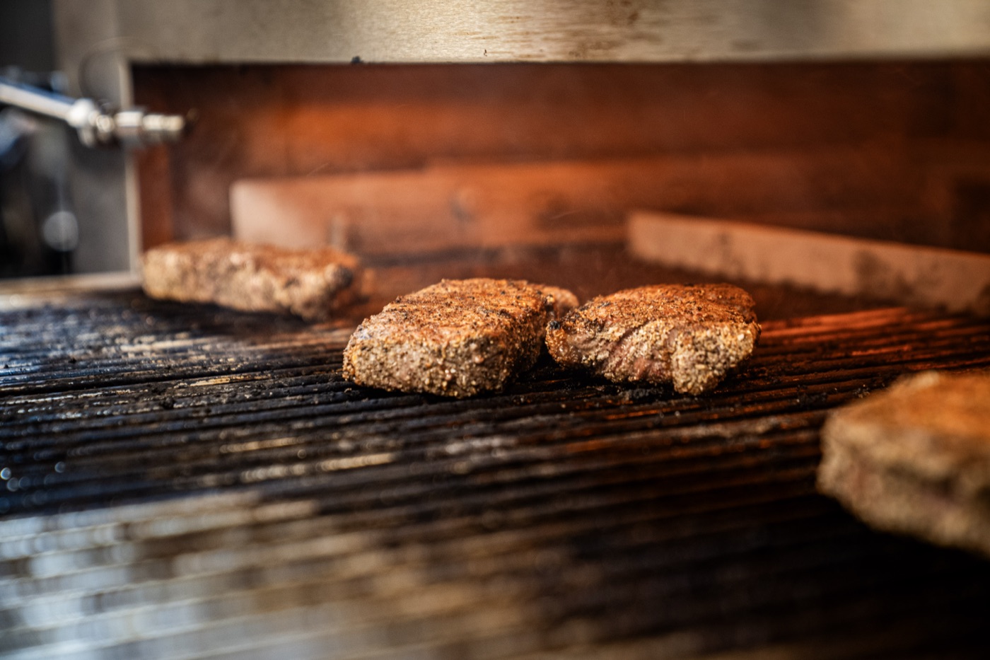 Peppercorn-crusted steaks searing on the 1,800°F infrared broiler at Little Alley Steak Roswell